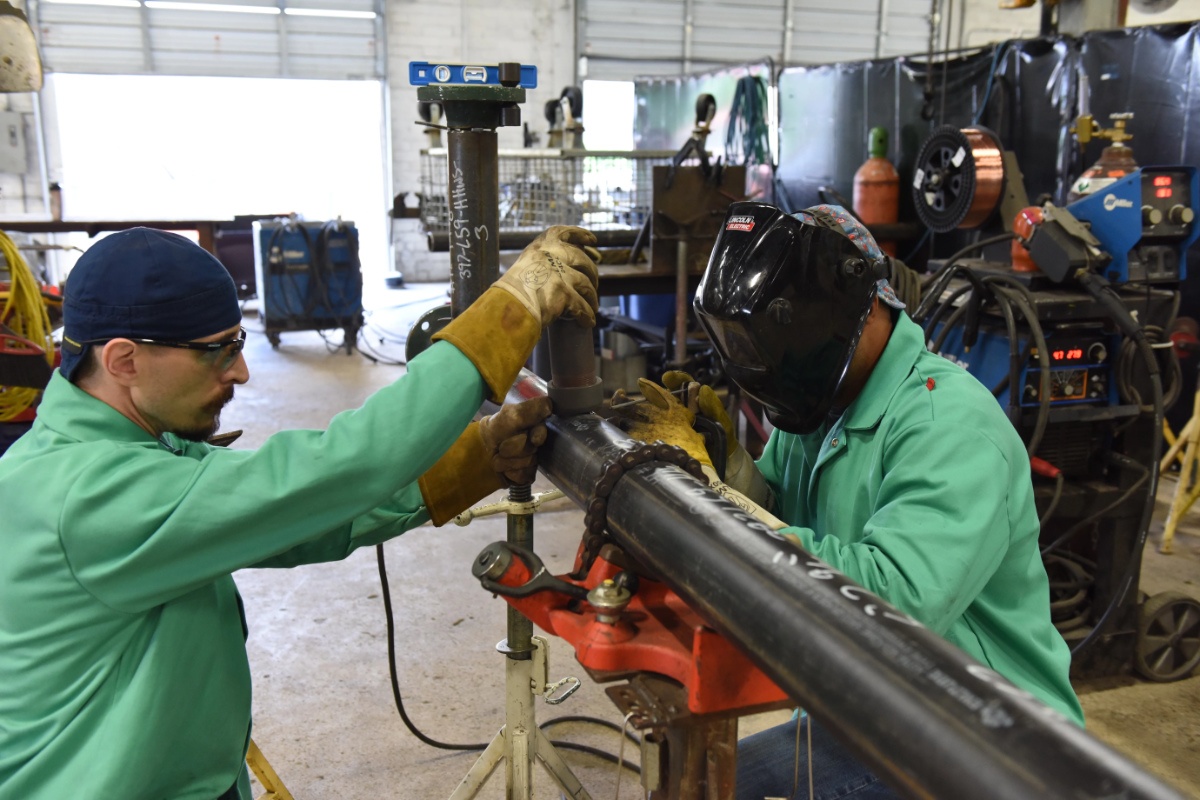 Image of two protected individuals cutting a pipe